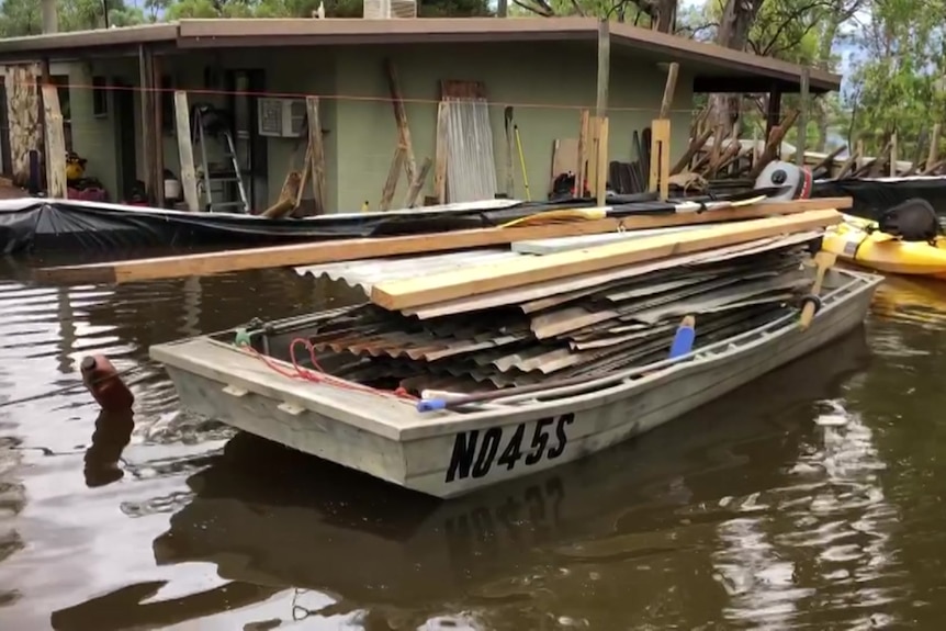 A boat with wood and metal on it near a house