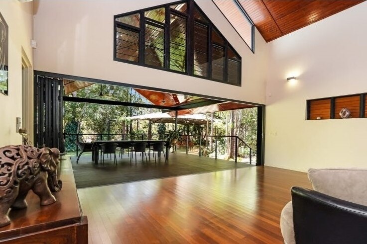A high-ceilinged living space with deep brown floorboards and a dining table.