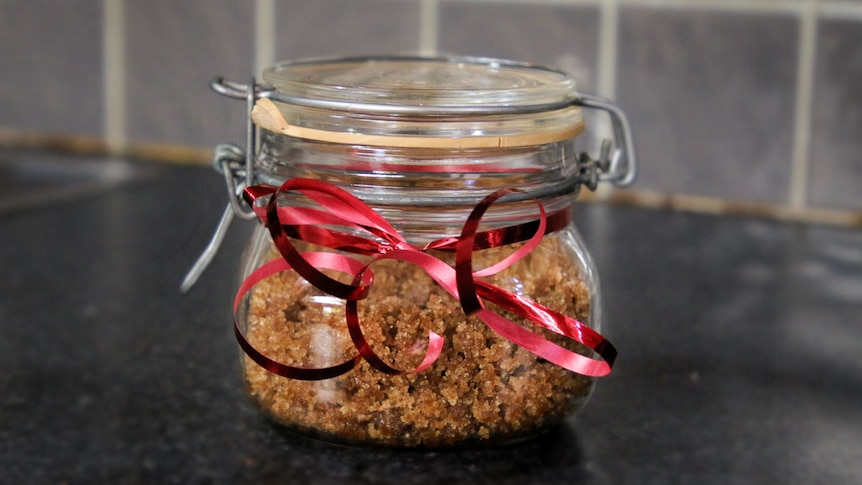 Pumpkin spice sugar scrub in a jar with a red Christmas bow