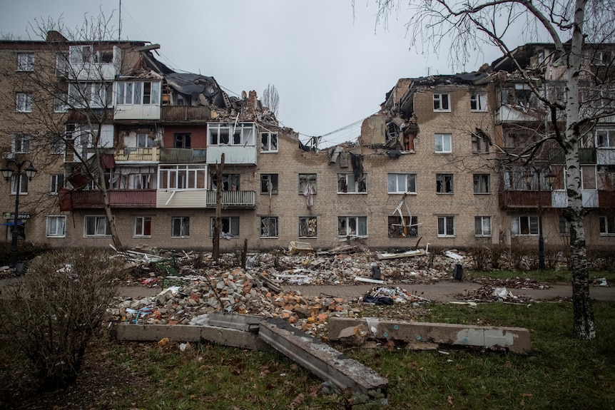 A residential building with several storeys missing or damaged by a military strike.