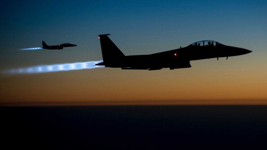 Two US Air Force F-15E Strike Eagles fly over the Middle East at dusk.