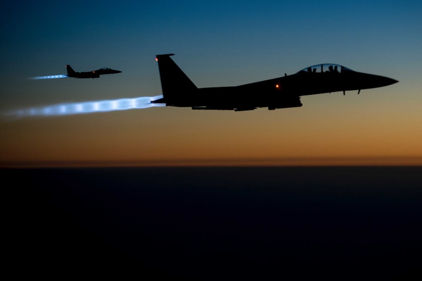 Two US Air Force F-15E Strike Eagles fly over the Middle East at dusk.