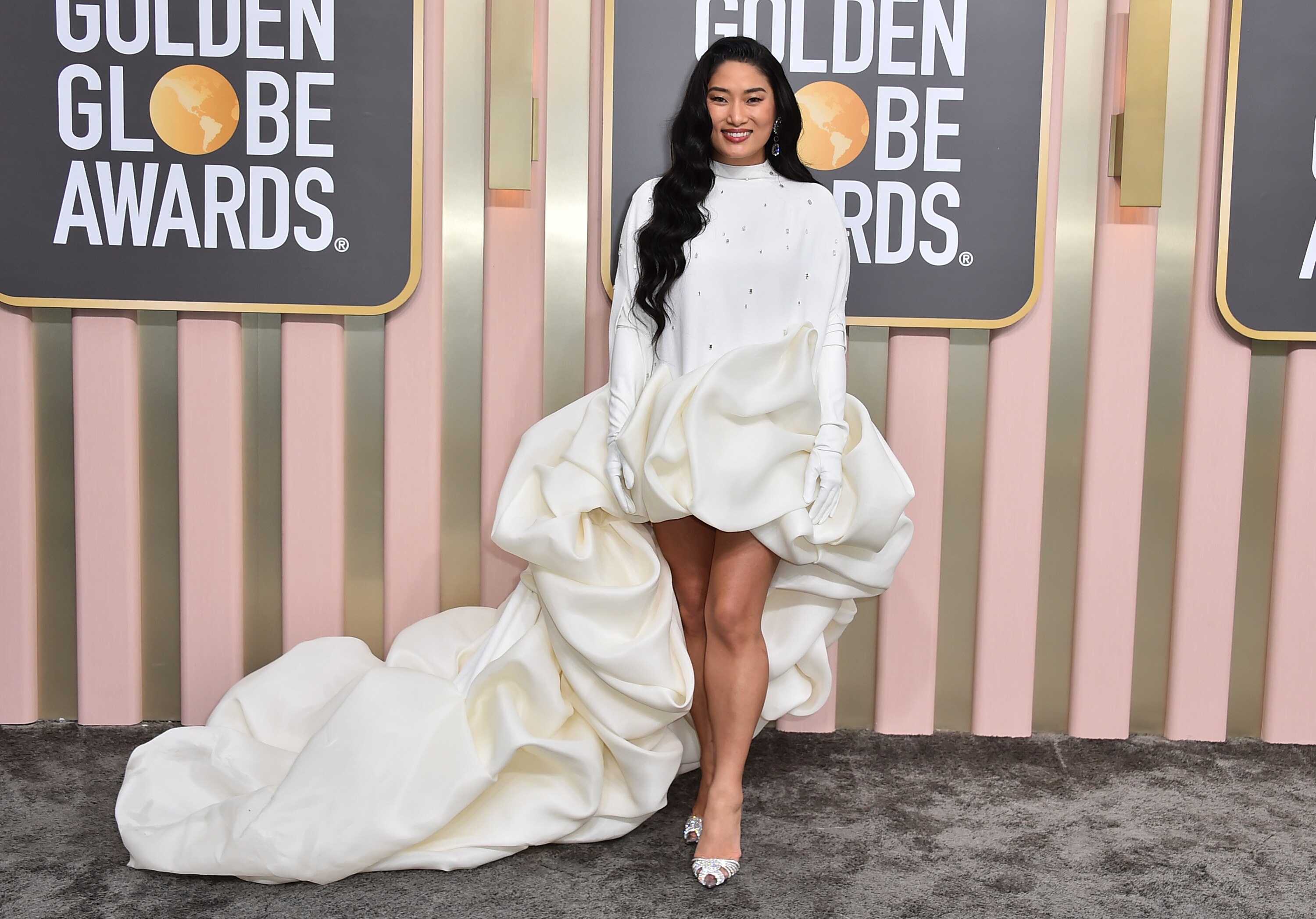 Chloe Flower wearing a long-sleeved short white gown with a long, fluffy train.