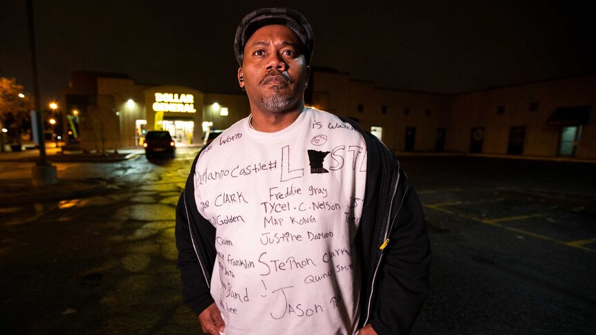 A man in a shirt bearing the names of people who have been shot dead by police in the US