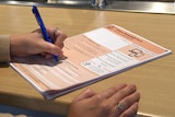 A hand holds a pen to an orange Australian census form.