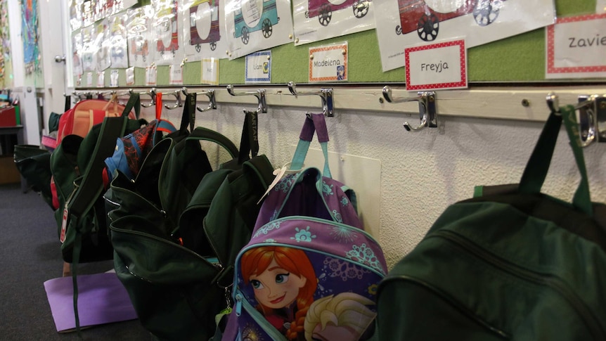 Bags hang on hooks outside a classroom.