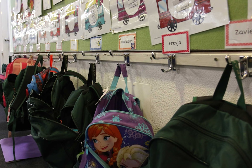 Bags hang on hooks outside a classroom.