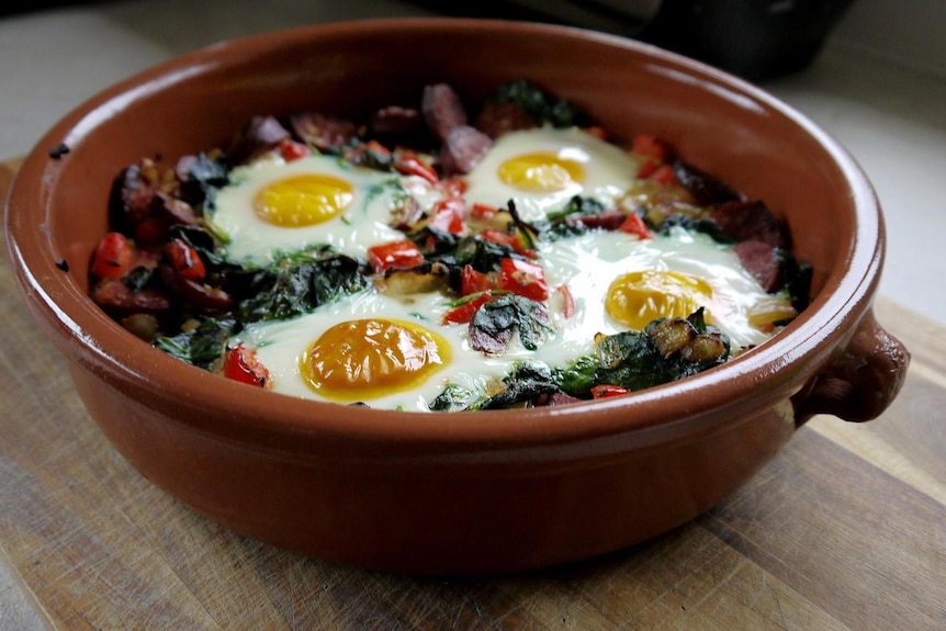 Four baked eggs in a pot.