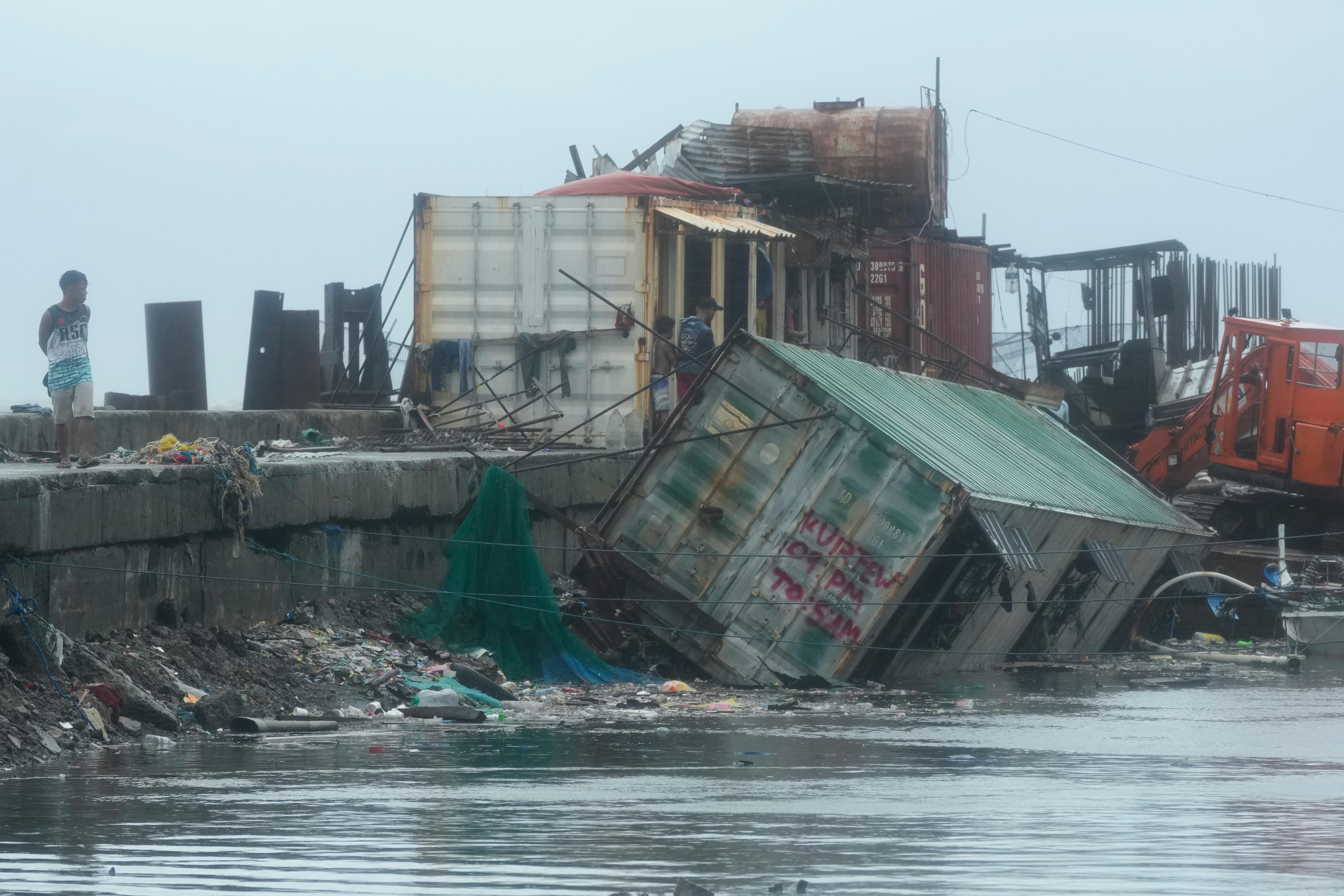 Um contêiner no oceano em um porto, cercado por lixo e detritos