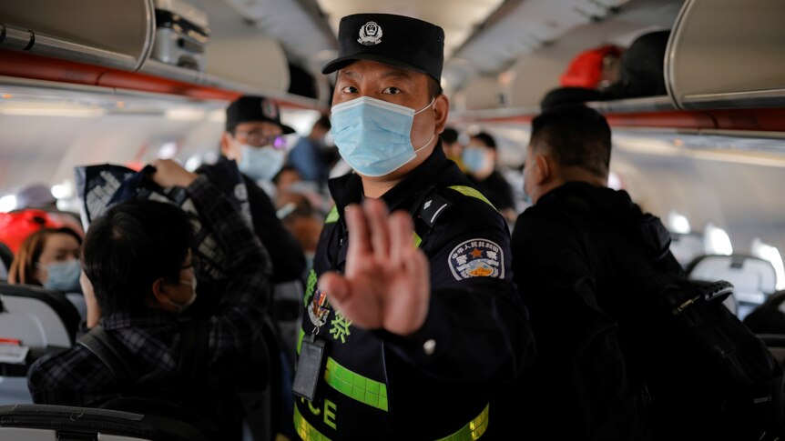 A Chinese police officer puts his hand up to order journalists off a plane in Xinjiang, China.