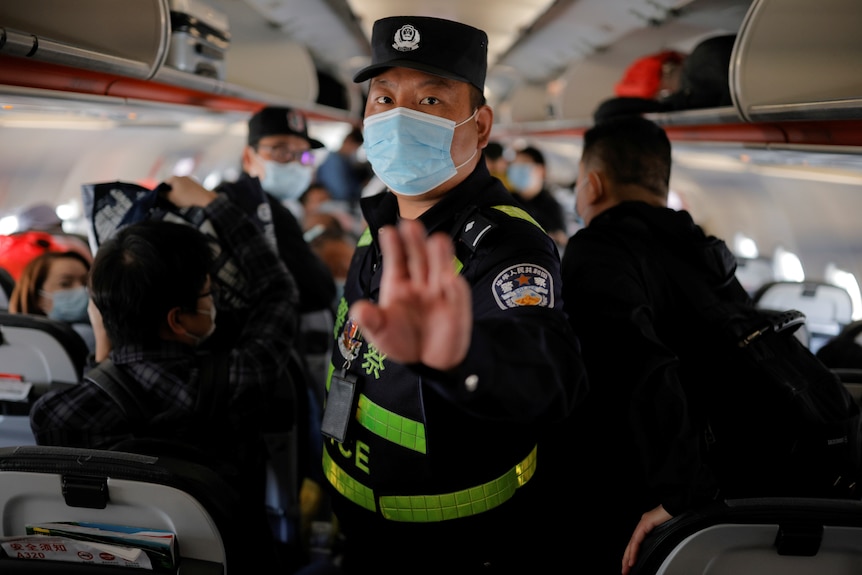 A Chinese police officer puts his hand up to order journalists off a plane in Xinjiang, China.