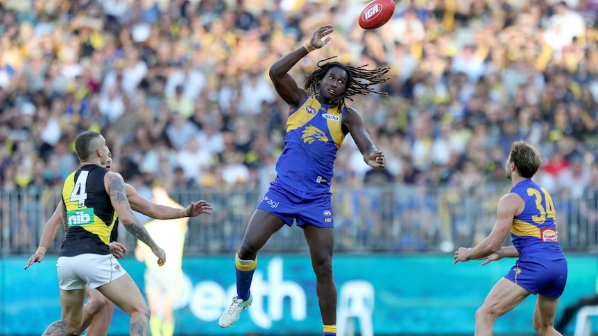 West Coast ruckman Nic Naitanui taps a football towards his teammate during a game against Richmond.