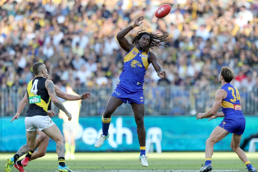 West Coast ruckman Nic Naitanui taps a football towards his teammate during a game against Richmond.