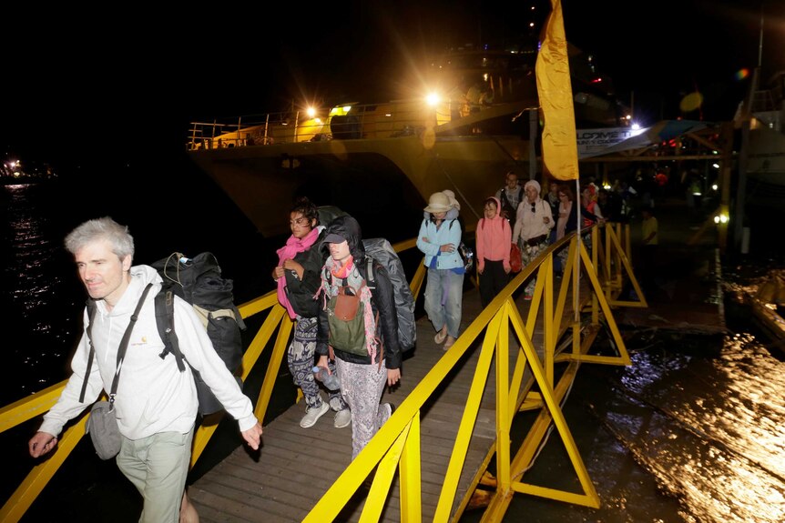 Tourists disembark boat on Gili Air beach after Indonesian quake