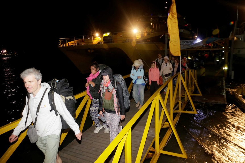 Tourists disembark boat on Gili Air beach after Indonesian quake