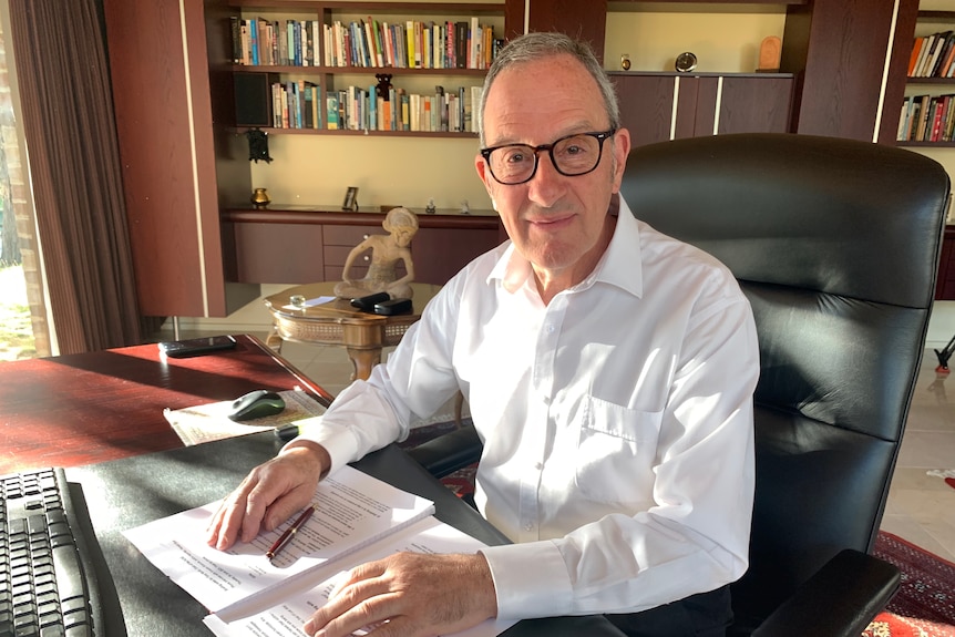 A man in a suit with law books behind him.