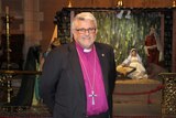 Richard Condie, Anglican Bishop of Tasmania, in front of a nativity scene.