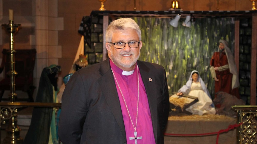Richard Condie, Anglican Bishop of Tasmania, in front of a nativity scene.