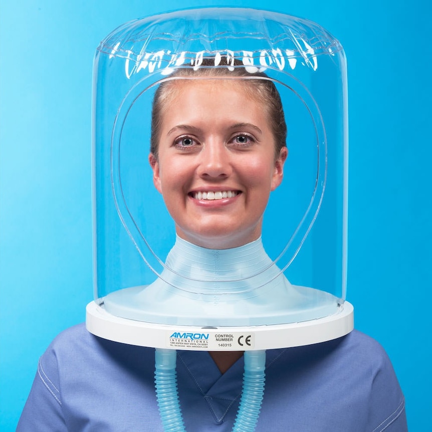 A woman's smiling face with a plastic tent-like covering.