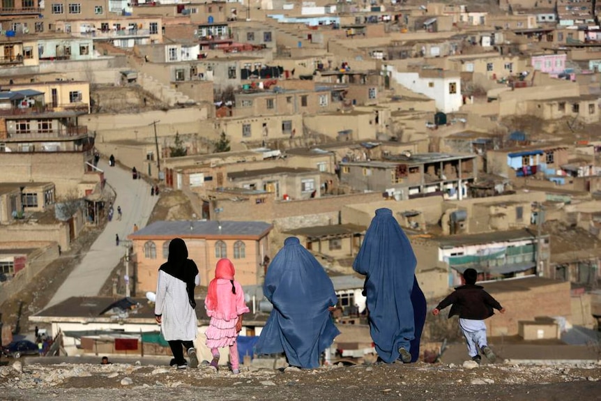 Burqa-clad women walk on Nadir Khan hilltop overlooking Kabul.