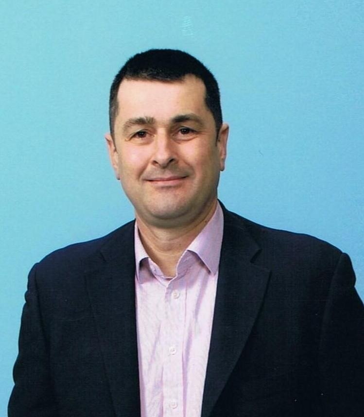 Portrait of white man with dark hair and fair skin in suit and open-neck shirt