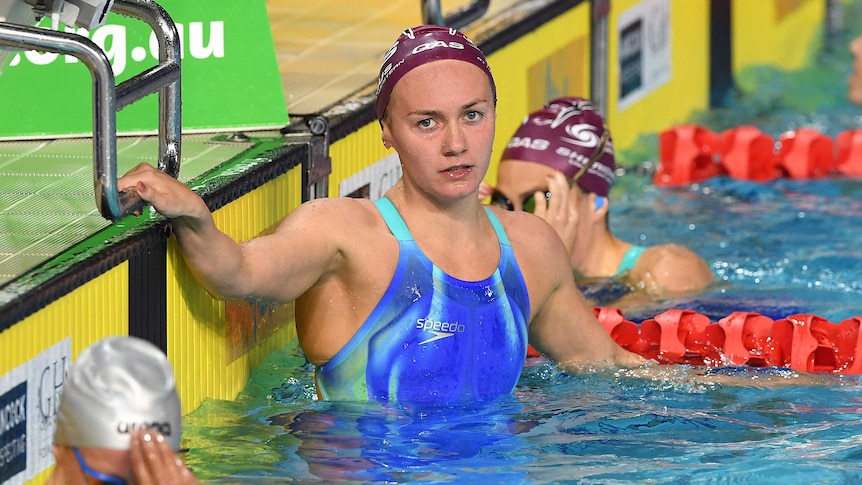 Ariarne Titmus holds on to the blocks after completing her race.