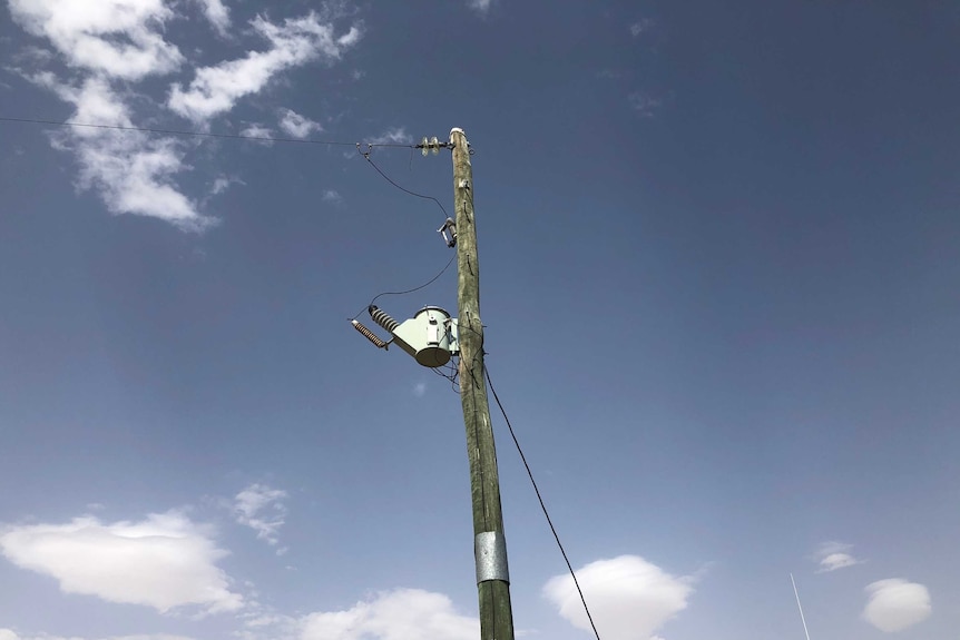 A power line with one line leaving it on a property.