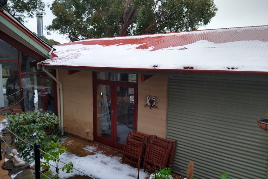 A house with hail accumulating on the roof of a house