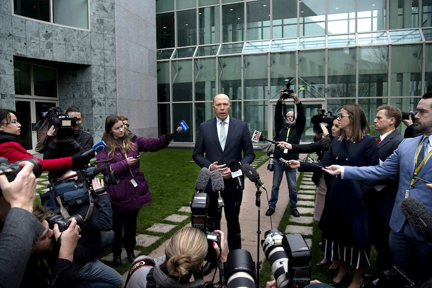 A wide shot showing Peter Dutton speaking to many journalists and cameramen outside Parliament