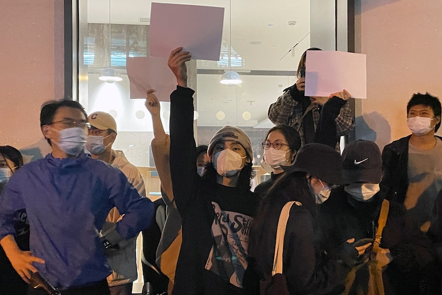 A group of people hold up blank white sheets of paper.