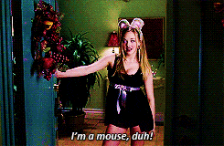 A blonde girl wearing a low-cut dress and mouse-ear headband opens a door. Text says 'I'm a mouse, duh.''