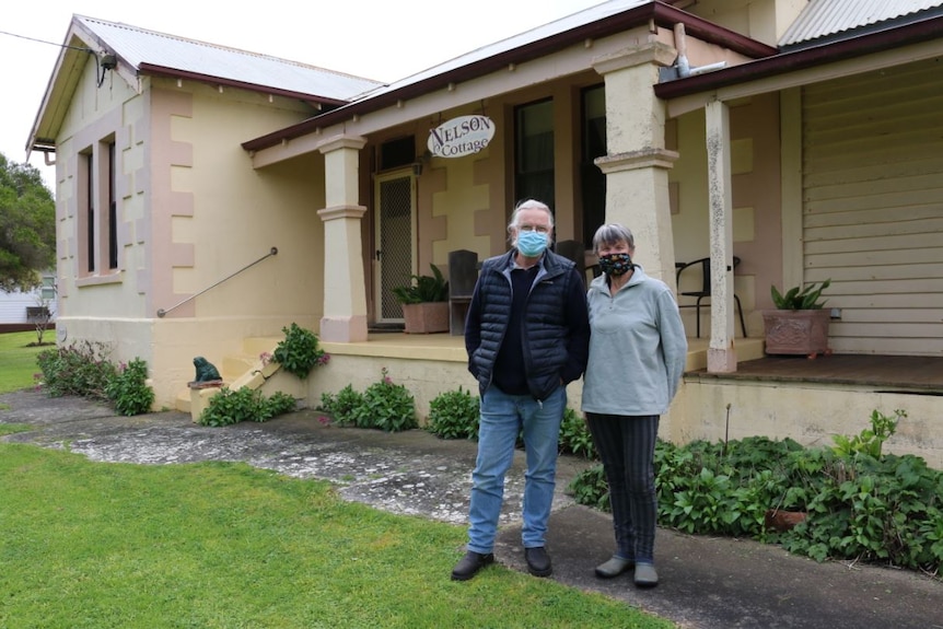 A man and a woman standing in front of historic Nelson Cottage.