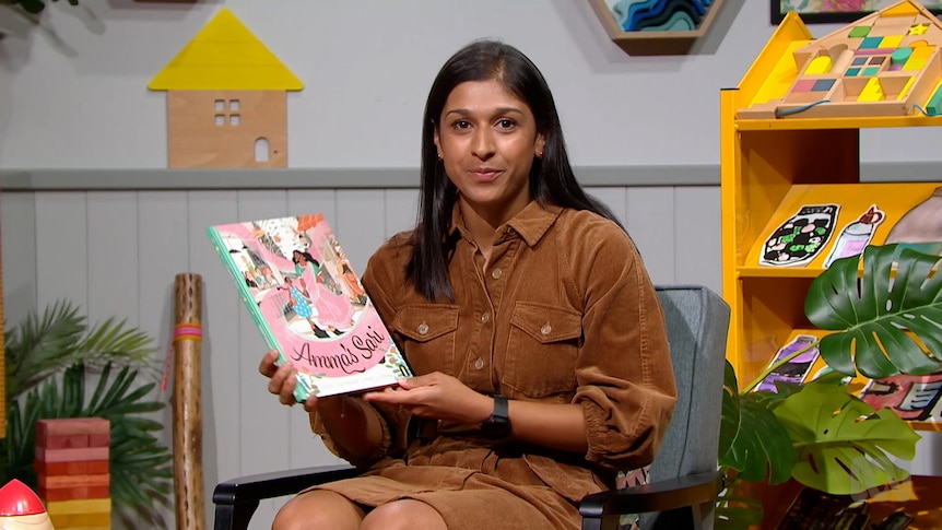 Teacher Vindyha Singh holds up story book, Amma's Sari