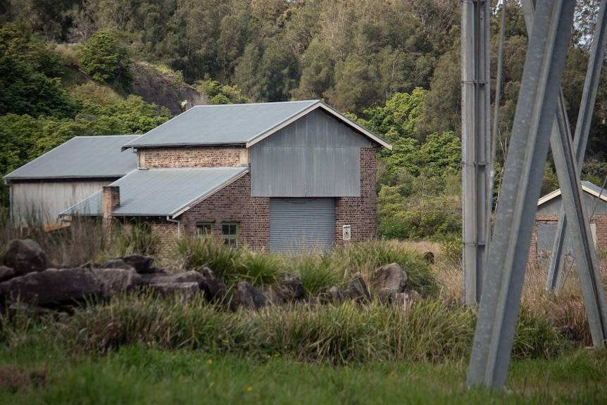 A brick building surrounded by bush