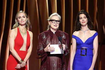 Three women stand on stage.