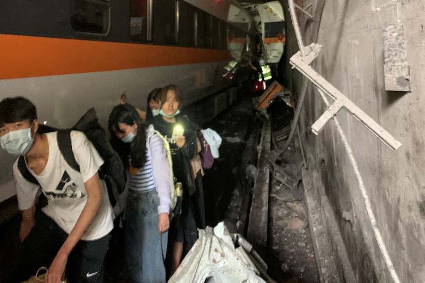 Des gens marchent à côté d'un train qui a déraillé dans un tunnel