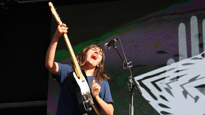 Courtney Barnett playing guitar and singing on stage at Byron Falls Festival