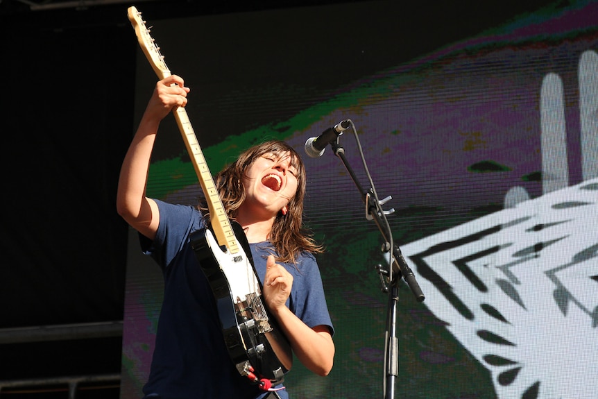 Courtney Barnett playing guitar and singing on stage at Byron Falls Festival