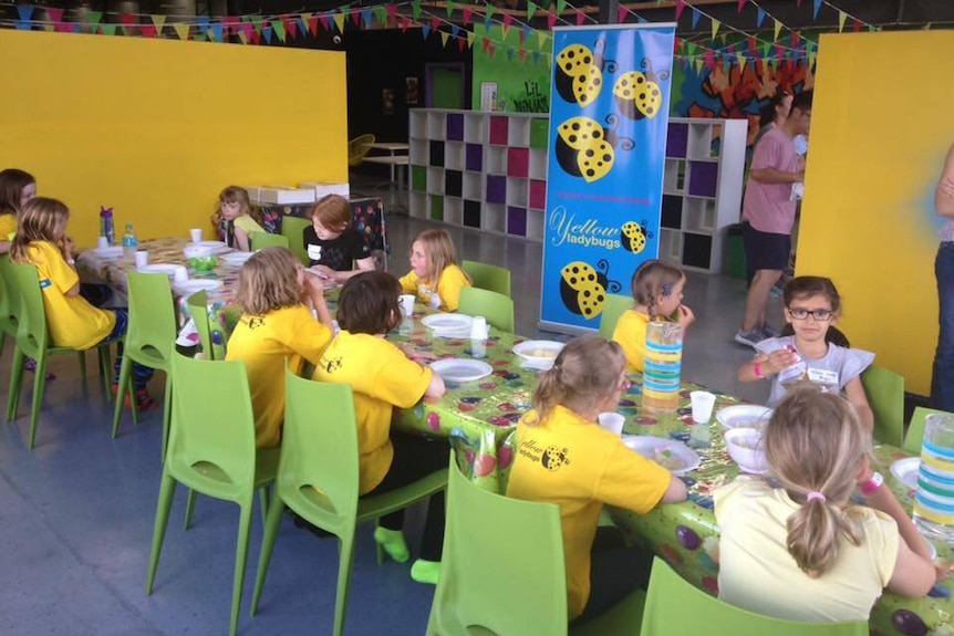 Young girls dressed in yellow sitting around a table