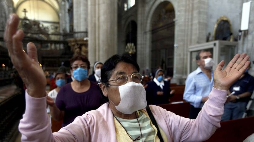 People wear face masks as a preventative measure against swine flu as they attend a mass