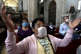 People wear face masks as a preventative measure against swine flu as they attend a mass