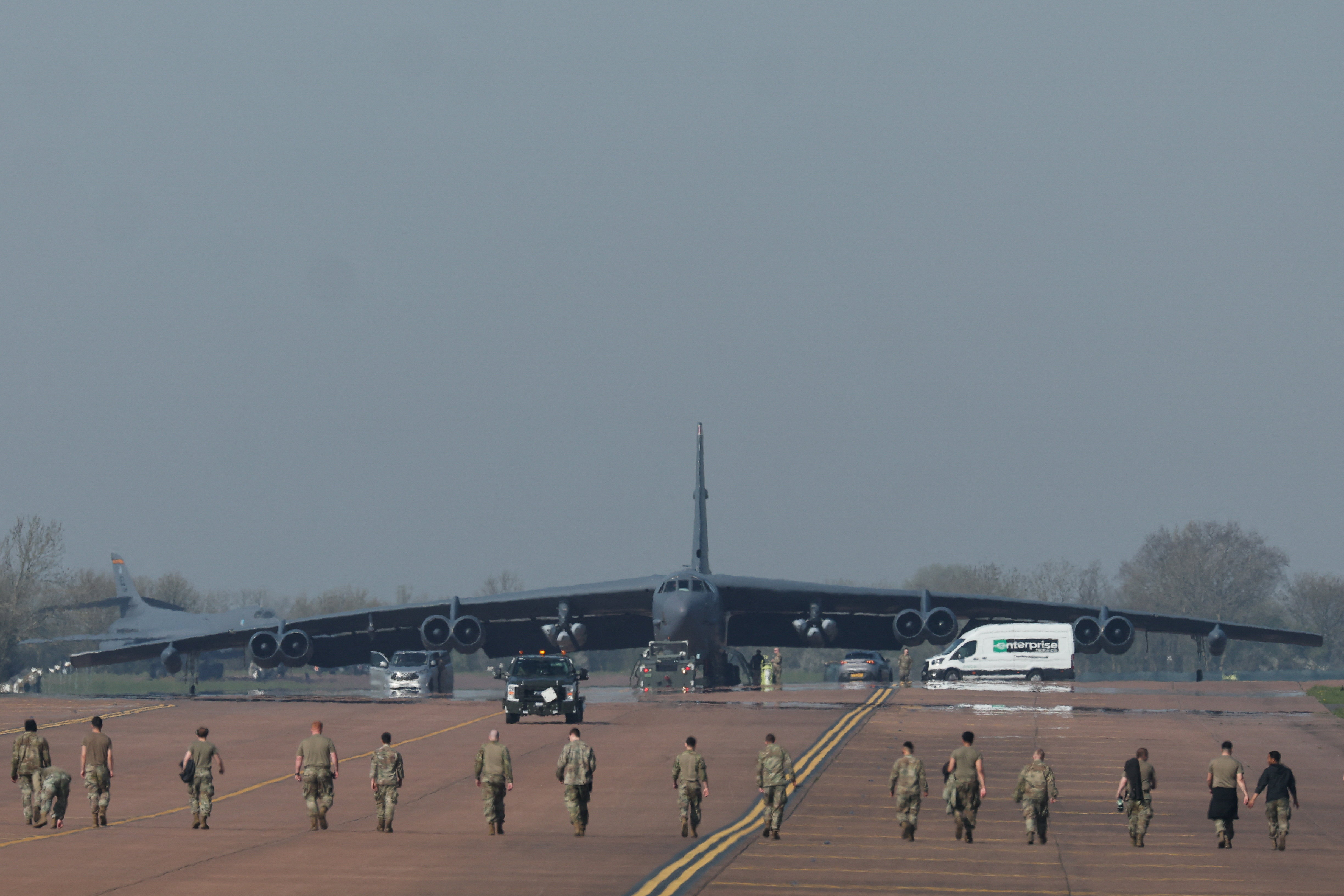 Men walking in a line towards a huge dark grey bomber aircraft