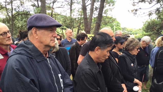 Mourners bow their heads at a ceremony to observe the loss of trees.