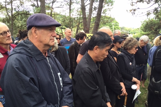 Mourners bow their heads at a ceremony to observe the loss of trees.