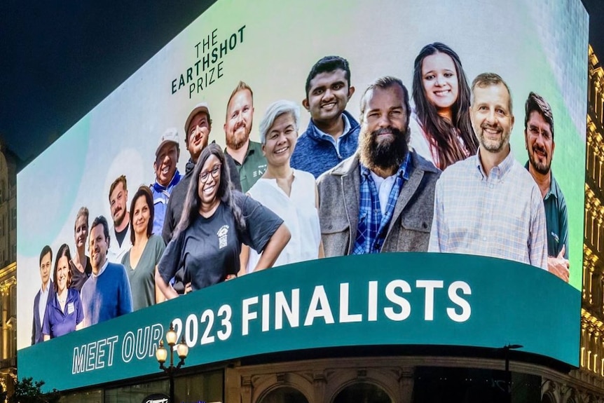 A digital billboard showing 15 people alll smiling and text above says "Earthshot Prize"