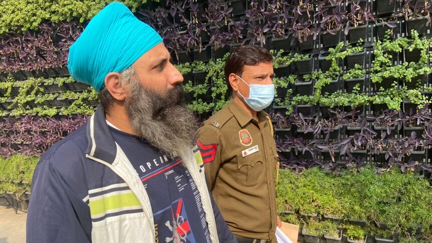 Rajwinder walks hand in hand with a masked security guard