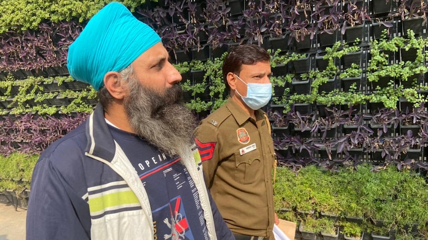 Rajwinder walks hand in hand with a masked security guard