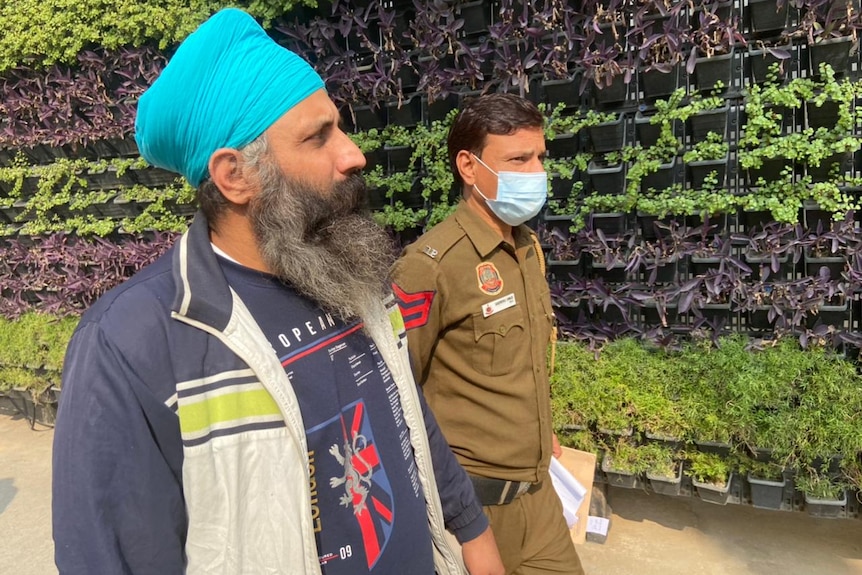 Rajwinder walks hand in hand with a masked security guard