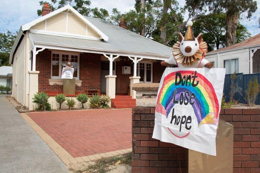 Rainbow don't lose hope sign with clown dog sits on a front fence