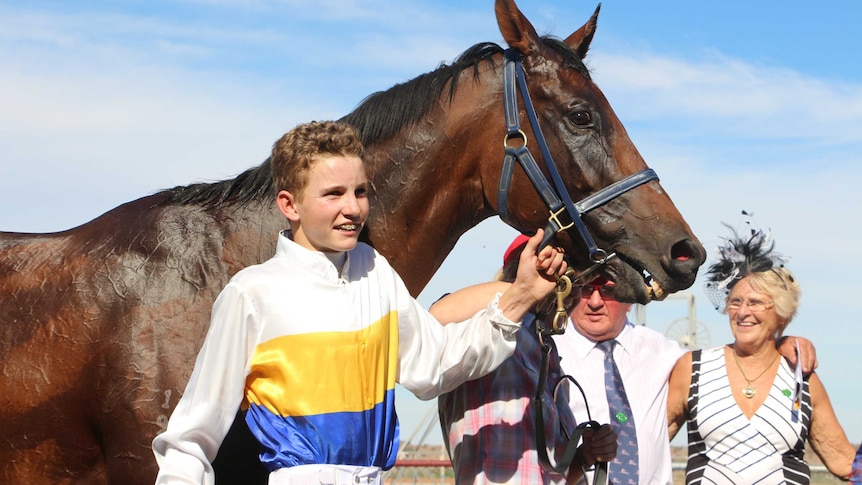 16-year-old jockey Justin Huxtable standing next to the horse he rode in the Outback Cup, It's Fred.